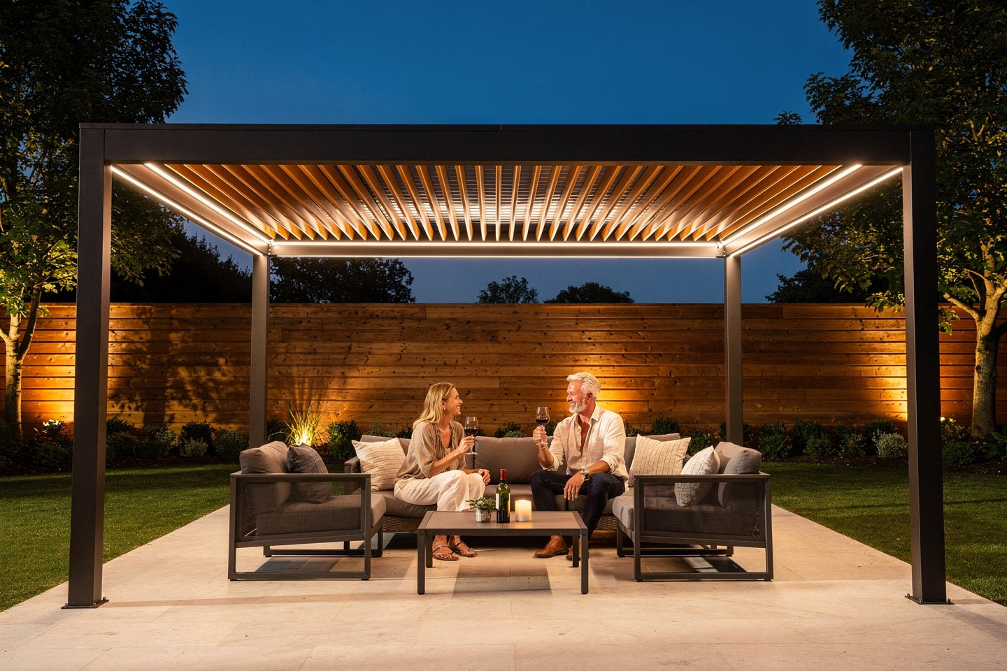 Couple enjoying wine at dusk under a motorized aluminum louvered pergola with integrated LED lighting
